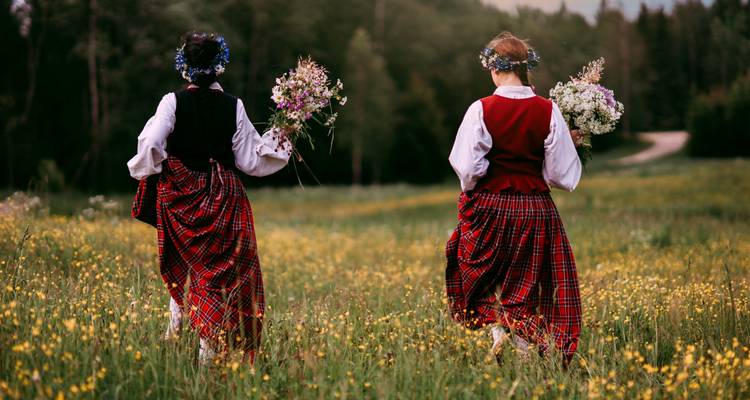 Twee vrouwen in traditionele kleding lopen in een veld met bloemen.