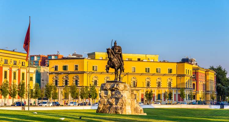 Die Skanderbeg-Reiterstatue steht vor leuchtend gelben Regierungsgebäuden auf dem Hauptplatz von Tirana.