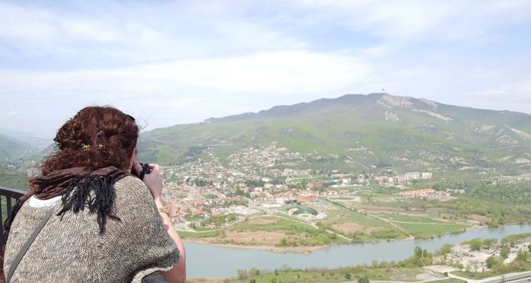 Personne photographiant une vue panoramique de ville avec des montagnes.