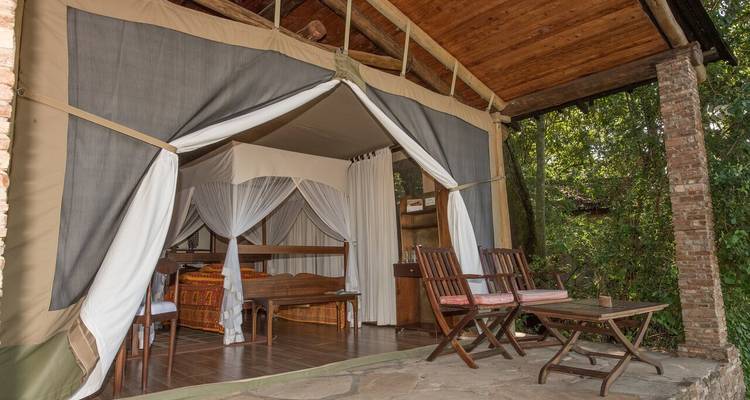 Een luxueuze tent met stoelen en een bed in een resort.