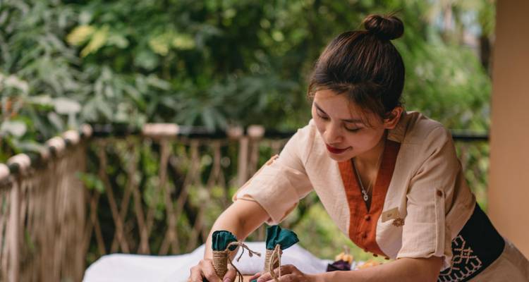 Een vrouw die decoratieve voorwerpen op een dienblad buitenshuis schikt.