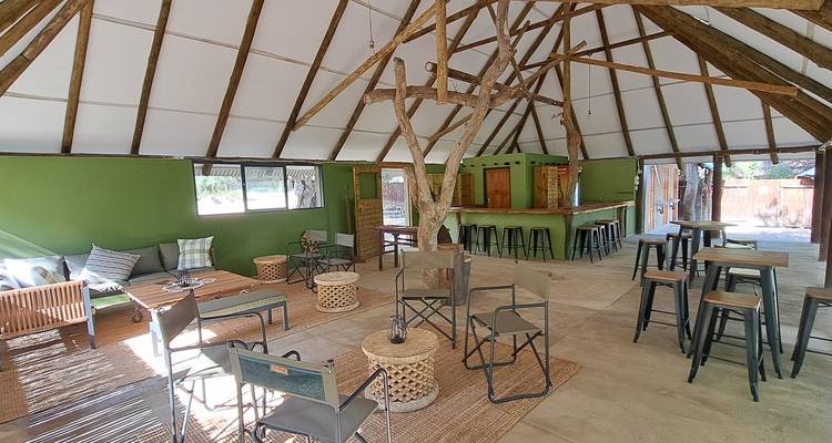 Intérieur chaleureux d'un chalet avec des sièges rustiques et un plafond en bois.