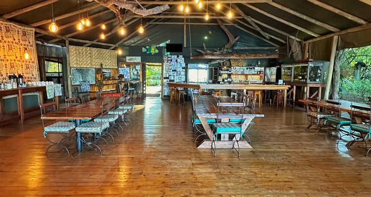 Salle à manger spacieuse dans un lodge ouvert, éclairage chaleureux et intérieurs en bois.