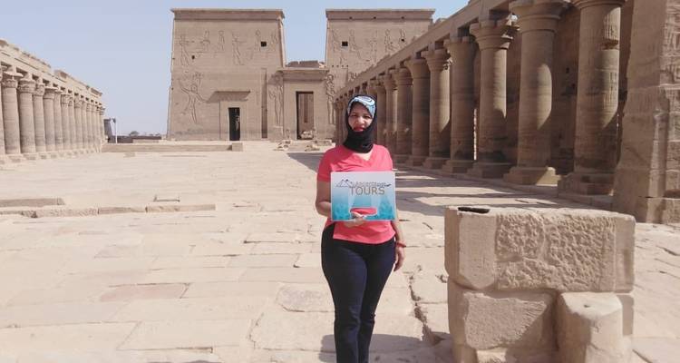 Vrouw die een toeristenbord vasthoudt bij een oude Egyptische tempel.