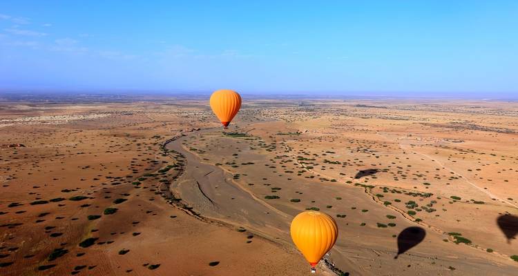 Heißluftballons, die über eine Wüstenlandschaft fliegen.