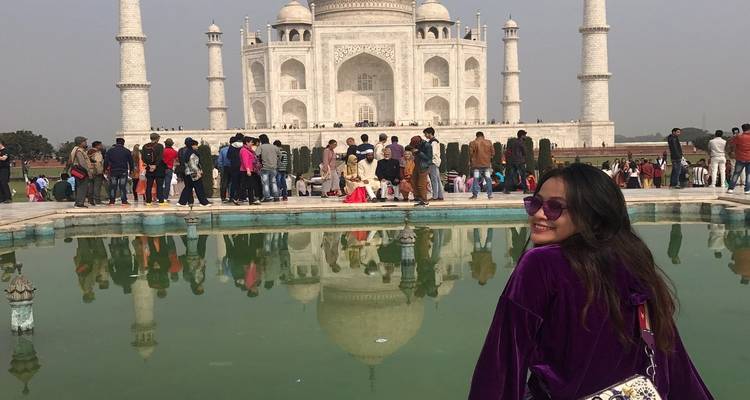 Tourist smiling with a famous mausoleum in the background.