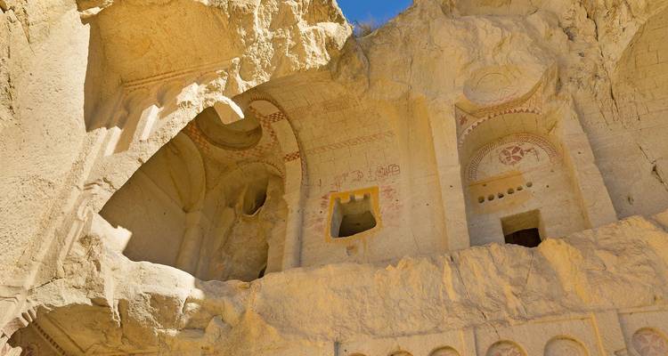 Intérieur d'église creusée dans la roche avec fresques estompées et ouvertures de fenêtres dans les falaises de tuf de la Cappadoce.