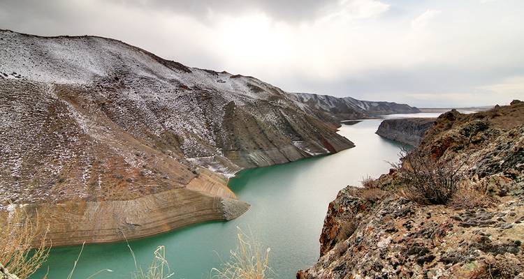 Wide river cutting through snowy mountainous terrain.
