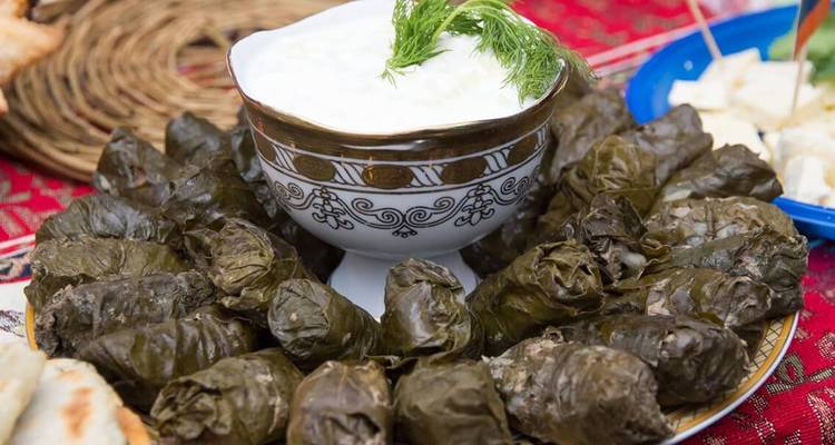 Dish of stuffed vine leaves with sauce.