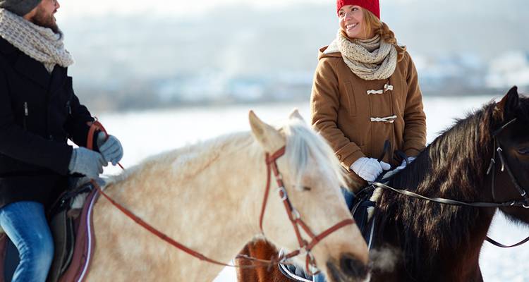 Two people on horseback in a snowy landscape