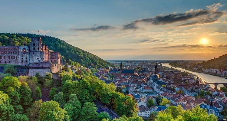 Panoramisch uitzicht op een middeleeuws kasteel met uitzicht op een rivierstad bij gouden zonsondergang in Duitsland.