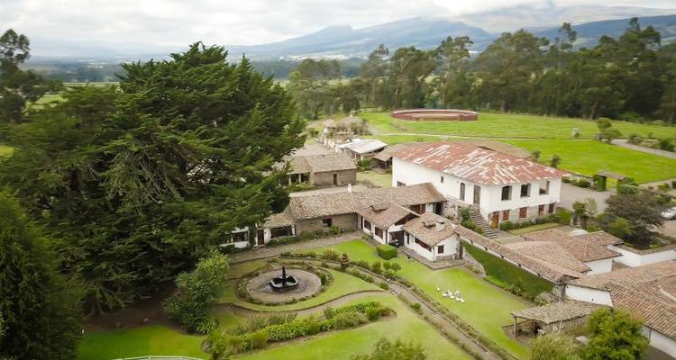 Vue aérienne d'un domaine rural avec des bâtiments traditionnels et des arbres.