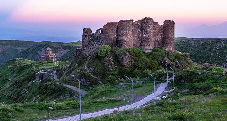Ancient ruins on a hill with a scenic landscape at sunset