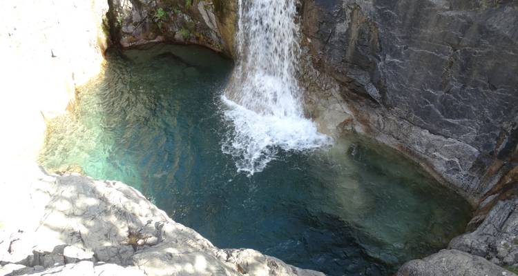 Une cascade qui se déverse dans un bassin limpide entouré de rochers.