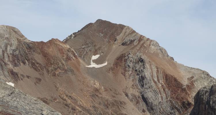 Un sommet de montagne avec des formations géologiques diversifiées sous un ciel dégagé.