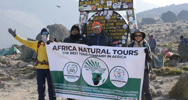Groep mensen die een spandoek vasthouden met de Kilimanjaro op de achtergrond.