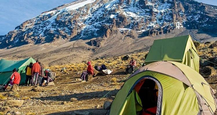 Kampeerscène met tenten en de Kilimanjaro op de achtergrond.
