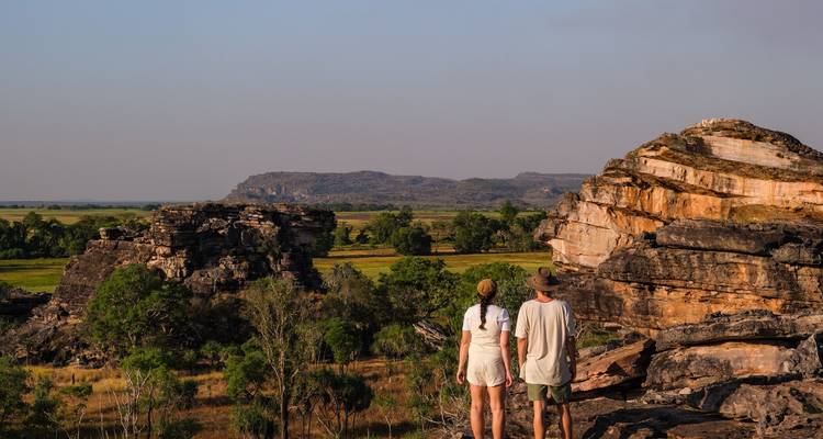 Reizigers kijken uit over uitgestrekte wetlands en zandstenen rotsformaties in Kakadu National Park.