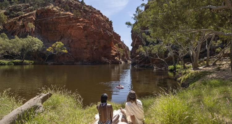 Gorge tranquille avec nageurs et kayakiste entre des falaises de roche rouge reflétées dans l'eau calme