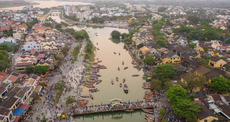 Vista aérea del frente fluvial de Hoi An lleno de botes y peatones durante la luz del atardecer.