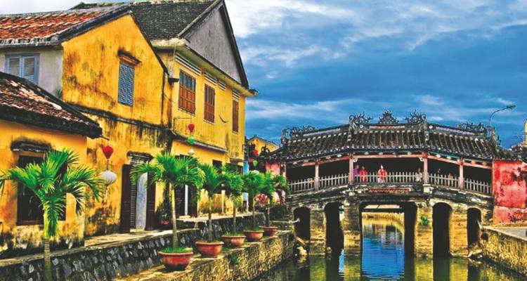 Bâtiments traditionnels colorés et un pont historique au-dessus d'une rivière.
