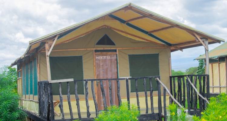 Tente-cabane avec un petit porche dans un cadre naturel.
