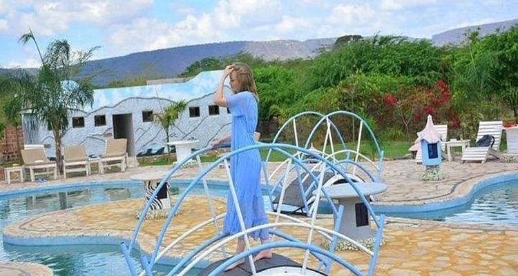 Person in blue dress on a bridge over a pool.