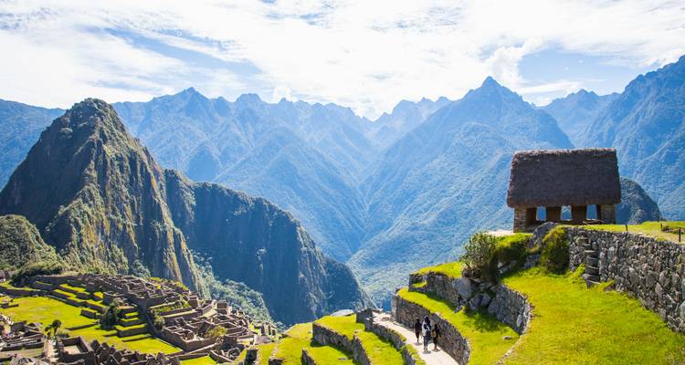 Een breed uitzicht op Machu Picchu's stenen terrassen met uitstekende ruige bergen onder een heldere hemel.
