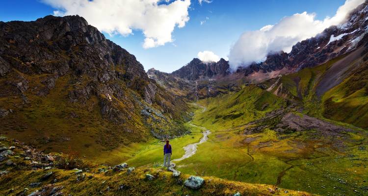 Persoon op de voorgrond die uitkijkt over een uitgestrekte bergachtige vallei.