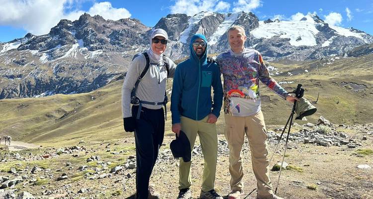 Trois trekkers posant devant les pics andins enneigés lors d'une journée brillante en haute altitude.