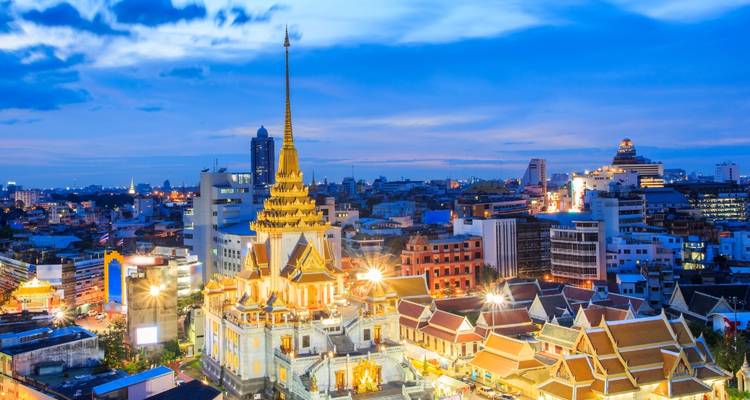 Temple illuminé au crépuscule avec horizon urbain en arrière-plan.