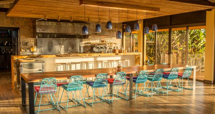 Stylish open kitchen and long wooden dining table bathed in warm afternoon light.