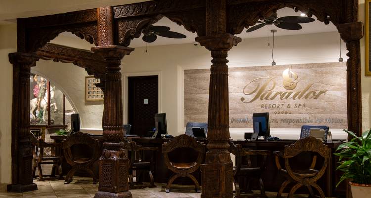 Elegant carved-wood reception desk area of a resort and spa with computers ready for guests.