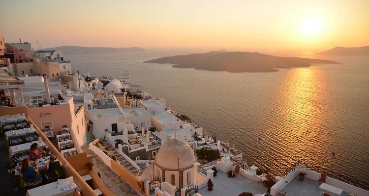 El pueblo de Oia en los acantilados blanqueados de Santorini brillando al atardecer sobre la caldera y el Mar Egeo