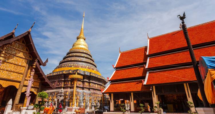 Buddhist temple with a golden stupa and bright red roofs under a clear blue sky.