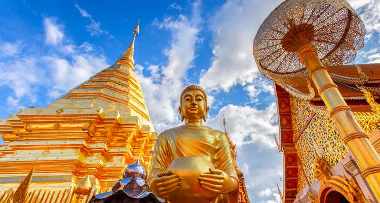 Golden Buddha statue and pagoda under a blue sky.