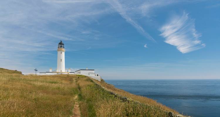 Vuurtoren op een kustklif met een heldere blauwe lucht.