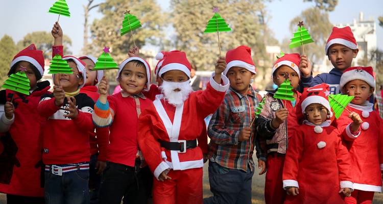 Children in Santa outfits holding festive decorations.