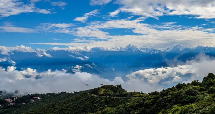 Himalayan view with clouds floating over lush green hills.