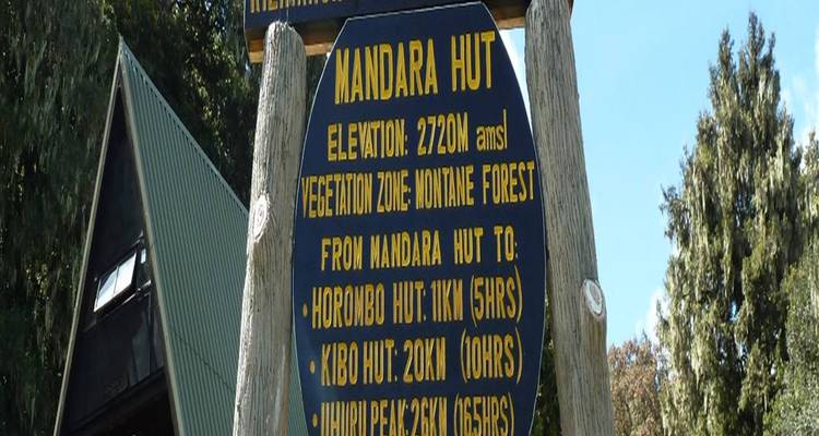 Wooden signboard details Mandara Hut elevation and trekking times on Kilimanjaro's Marangu Route.