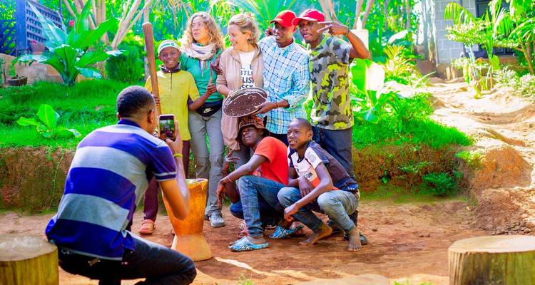 Visitors pose for a cheerful group photo during a hands-on cultural demonstration in a lush garden.