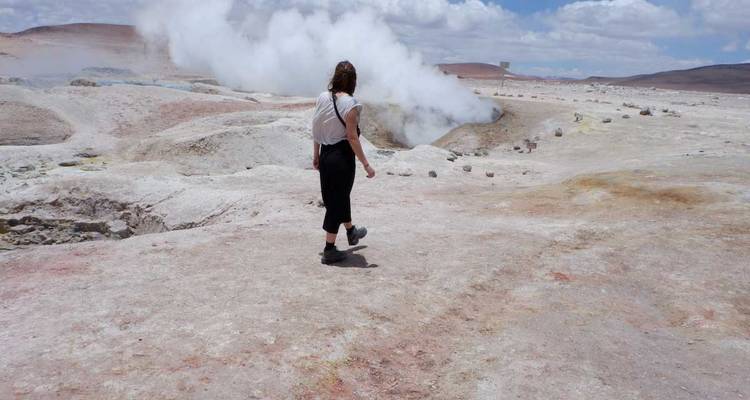 Person, die durch Dampfaustrittsöffnungen in einer wüstenähnlichen Gegend geht