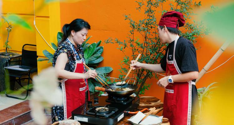 Dos personas cocinando con delantales en un entorno al aire libre.