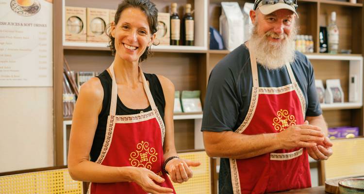 Un hombre y una mujer sonrientes con delantales, en interiores.