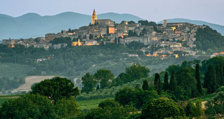Uitzicht op een historische stad op een heuvel tijdens de schemering.