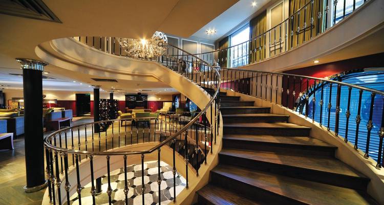 Intérieur élégant avec un majestueux escalier en spirale, un lustre et une décoration luxueuse à bord d'un navire de croisière fluviale.