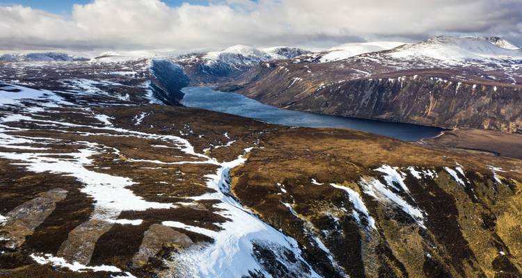 Luchtfoto van een ruig landschap met sneeuw en een meer.