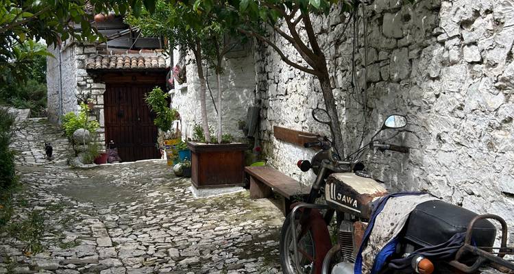 Cobblestone alley with a motorbike parked beside a rustic wooden door.