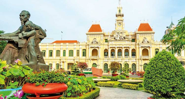 Ein großartiges Gebäude mit einer Statue und Gärten in Ho-Chi-Minh-Stadt.