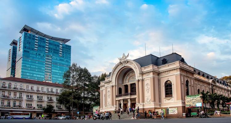 Die Vorderseite des Opernhauses von Saigon mit modernen Gebäuden im Hintergrund.
